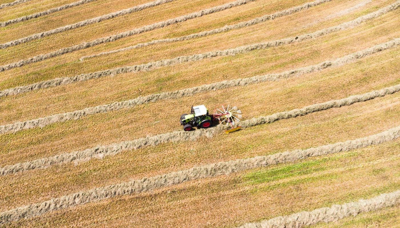 Tracteur agricole travaillant dans un grand champ vu du ciel