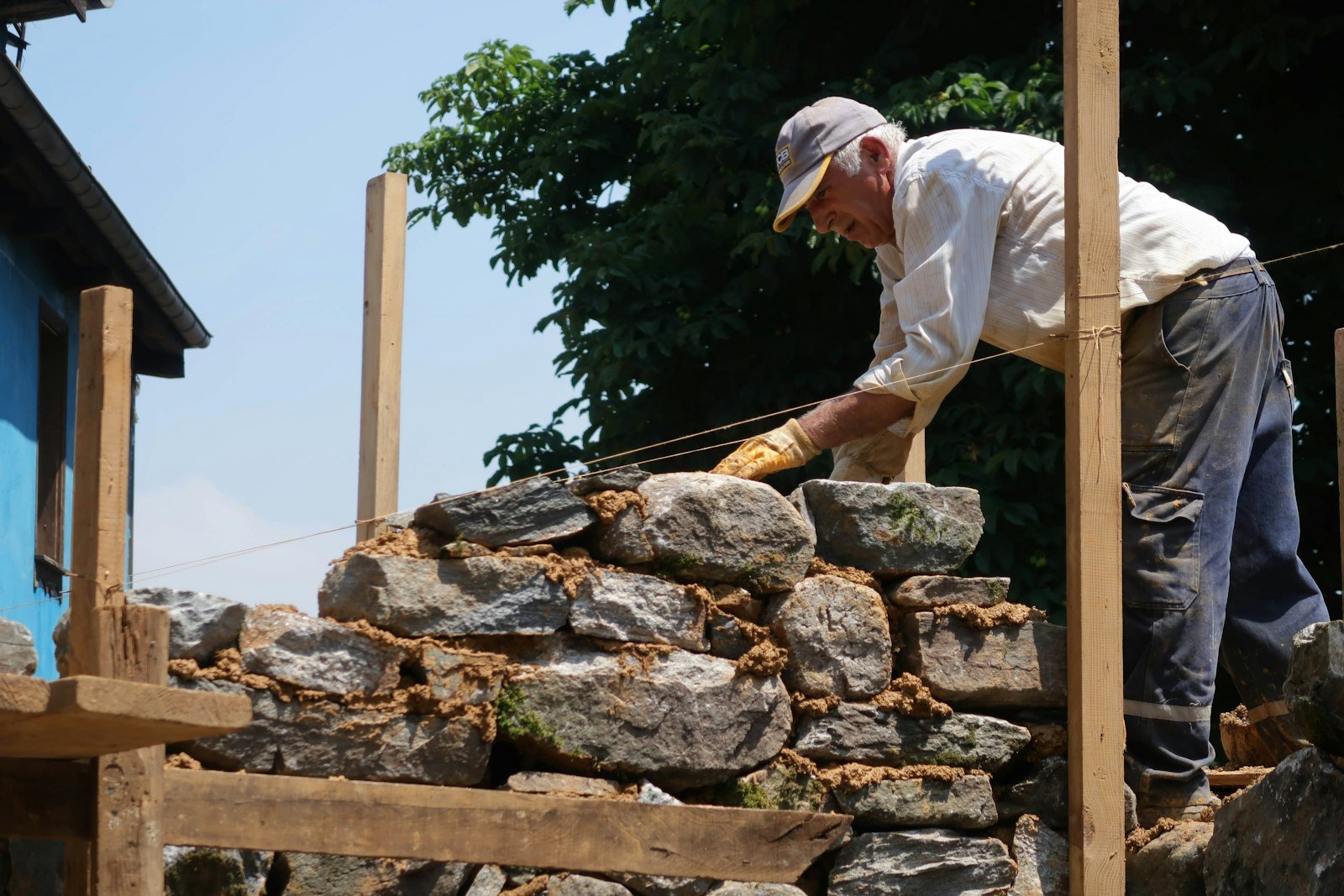 Ouvrier montant un muret en pierre sèche à l'extérieur